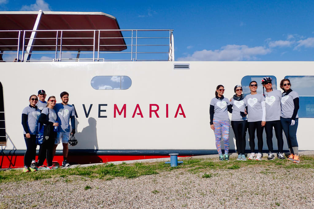 Cyclists in sportswear posing in front of the Ave Maria boat